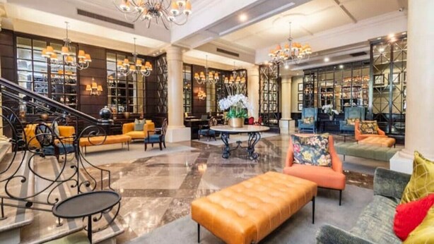 Eine geräumige Lobby mit einer imposanten Treppe, Sitzbereichen und einem Kronleuchter.