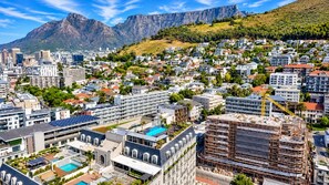A cityscape with residential buildings, a construction site, and a mountain in the background. - Green Point Luxury Suite Pool + V&A Waterfront (Cape Town)