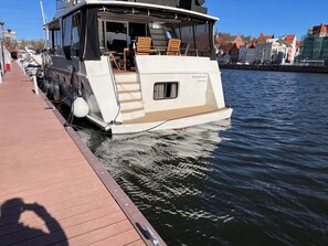 A boat docked at a pier with a covered deck area, a small window, and a name 'Moonflower Hamburg' on the side. - Beautiful accommodation in the center of Lübeck (Lübeck)