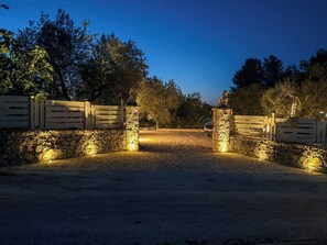 Ein verschlossener Eingang mit Steinmauern und einem Holztor, der zu einer gepflasterten Fläche führt.