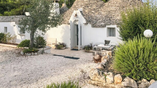 Un bâtiment blanc avec des toits en pierre et une allée gravillonnée.