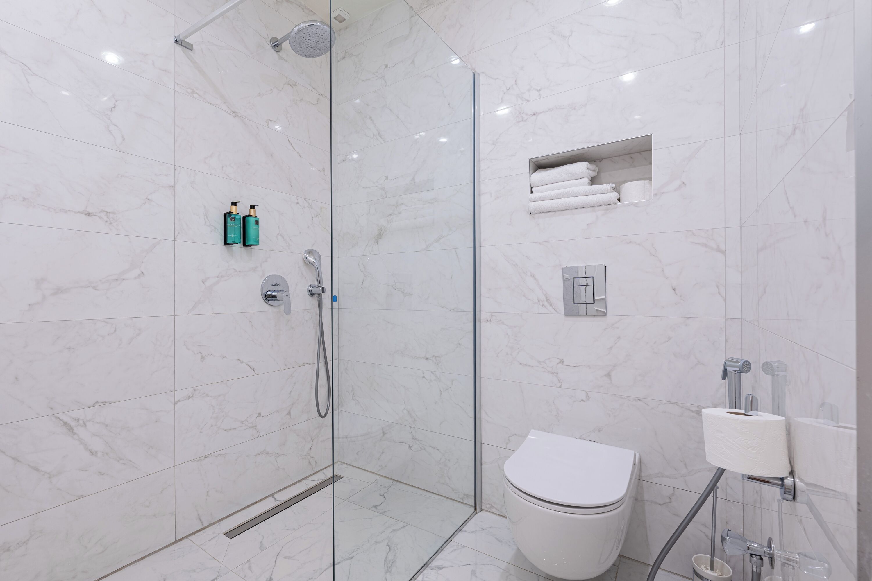 Un bagno moderno con doccia vetrata, un water e un lavandino con dispenser di carta.