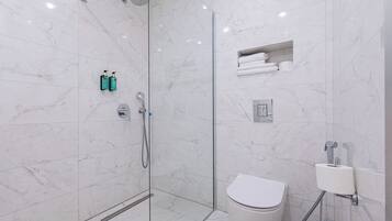Un bagno moderno con doccia vetrata, un water e un lavandino con dispenser di carta.