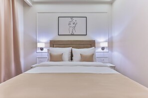 A neatly made bed with a headboard, two bedside tables with lamps, and a framed artwork on the wall. - Hotel Eden (Budva)