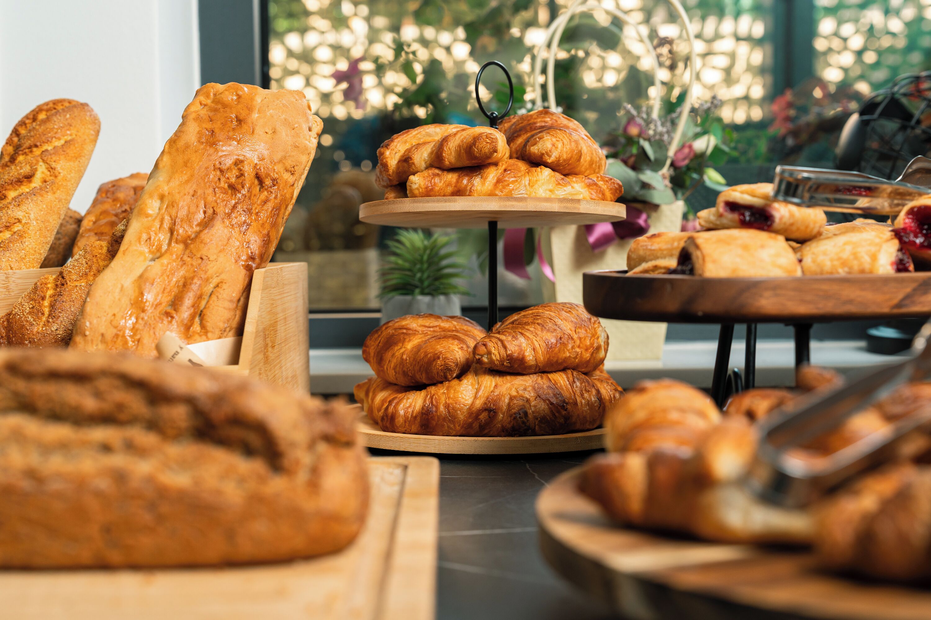 An assortment of baked goods including bread and croissants on wooden serving boards.