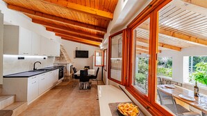 Una cocina moderna con armarios blancos, una chimenea de piedra y un comedor con mesa y sillas.