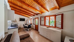 Cocina compacta con comedor, vigas de madera en el techo, televisor y vista a zonas verdes.