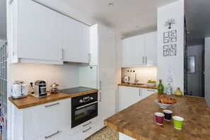 Eine moderne Küche mit weißen Schränken, einer Holz Arbeitsplatte, einem Toaster, einem Wasserkocher und einer Schüssel Croissants.