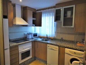 Eine kleine Küche mit Mikrowelle, Toaster, Spüle, Backofen und Geschirrspüler.