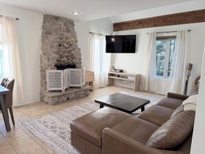 A living room with a stone fireplace, a flat-screen TV, a sofa, and a coffee table.