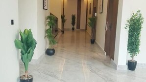 A hallway with marble flooring, potted plants, and framed artwork on the walls. - Casa Residence Al Narjees (Riyadh, Al Narjis neighborhood)