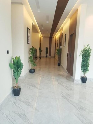 A hallway with marble flooring, potted plants, and framed artwork on the walls. - Casa Residence Al Narjees (Riyadh, Al Narjis neighborhood)