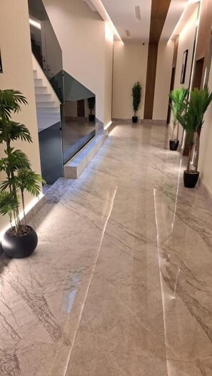 A hallway with marble flooring, potted plants, and a staircase. - Casa Residence Al Narjees (Riyadh, Al Narjis neighborhood)