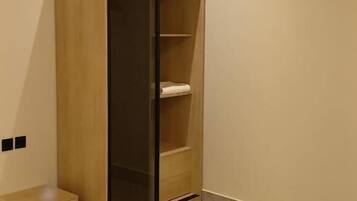 A room with a wooden wardrobe, a bed, and a small bench.