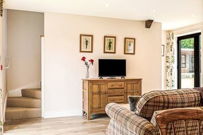 Un salon avec un meuble en bois, un téléviseur à écran plat et trois tableaux encadrés accrochés au mur.