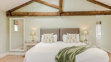 A bedroom with a large bed, two bedside tables with lamps, a mirror, and a window with curtains.