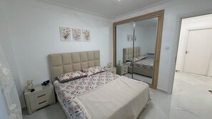 Ein Schlafzimmer mit einem Bett, Nachttischen, einem Spiegel und Wandbildern.
