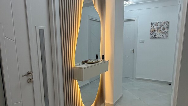 Ein modernes Badezimmer mit Waschtisch, Spiegel und Deckenleuchte.