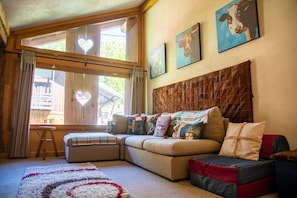 Una sala de estar acogedora con un sofá modular, una mesita y una ventana con cortinas.