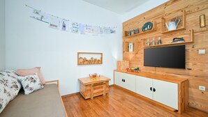 A child's room with a bed, a small desk, a TV, and a wall decorated with children's drawings.