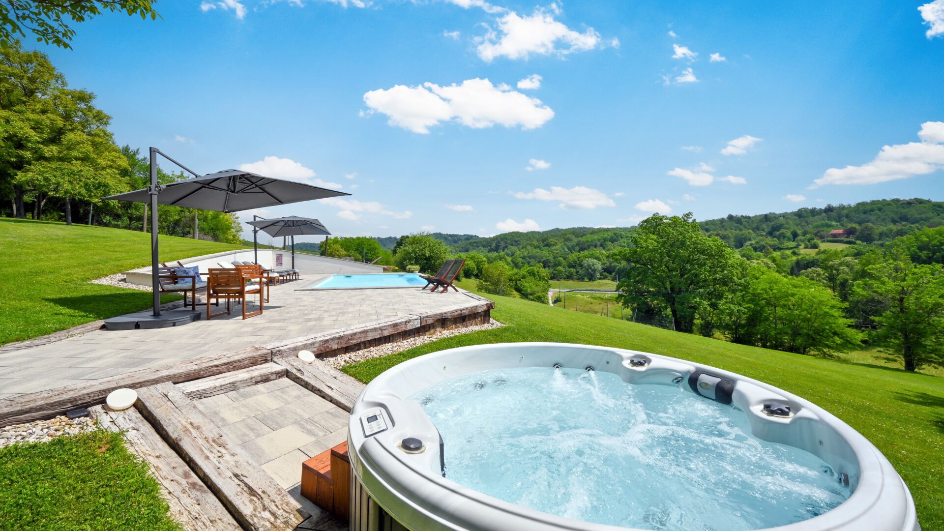 Un jacuzzi con piscina, mobiliario exterior y una vista panorámica.