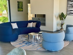 Ein modernes Wohnzimmer mit einem blauen Ecksofa, einem runden Couchtisch und einer Topfpflanze.