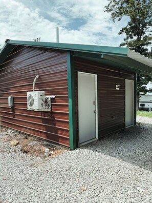 Il s’agit d’un petit bâtiment d’un seul étage, doté d’une façade métallique et d’un toit végétalisé. On y trouve une porte, un appareil de climatisation et une cheminée.