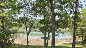 A wooden deck leading to a grassy area with trees and a body of water. - Bridges Camp - Private Beach! Dogs welcome! (Little Deer Isle)