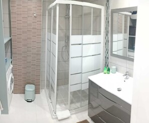 A modern bathroom with a glass shower enclosure, a white sink, and a mirror above it. - Beautiful 2-bedroom apart. with AC in enjoyable Los Cristianos 300m to the beach (Los Cristianos)