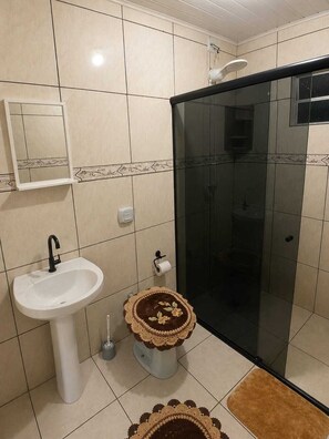 A bathroom with a white sink, toilet, and shower. - House on the big beach (São Francisco do Sul)