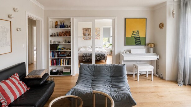 A modern living room with a sofa, a chair, a bookshelf, a desk, and a bed. - Bright and eclectic flat in Reykjavík - walk everywhere (Reykjavík)