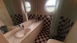 A bathroom with a checkered floor, a sink, a toilet, and two round windows. - Bright and eclectic flat in Reykjavík - walk everywhere (Reykjavík)