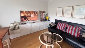 A living room with a TV, a sofa, a dining table, and a chair. - Bright and eclectic flat in Reykjavík - walk everywhere (Reykjavík)