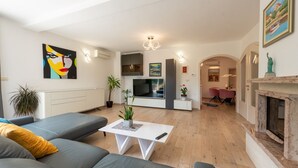 A modern living room with a grey sofa, a white coffee table, a flat-screen TV, and a fireplace. - Apartman Mihaela with pool by Villas Guide (Kuceli)