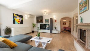 Ein modernes Wohnzimmer mit grauem Sofa, weißem Couchtisch, Flachbildfernseher und Kamin.