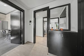Una cuina moderna amb un refrigerador negre gran, una zona de menjador amb tamborets i un passadís que condueix a un bany.