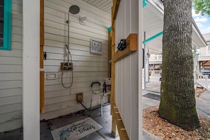 Eine Holzwand mit Dusche, Fußmatte und Baum.