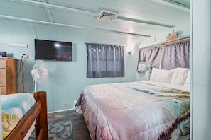 Ein Schlafzimmer mit einem Bett, einem Fernseher, einem Ventilator und einem Schild an der Wand.