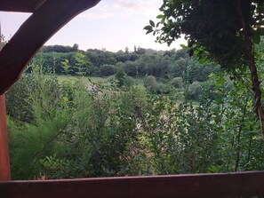 Une vue à travers une structure en bois, avec une végétation luxuriante et des arbres en arrière-plan.