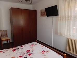 A bedroom with a bed, a wardrobe, a chair, a television, and a radiator. - Dorm 2 between Trega and Minho A GUARDA (A Guarda)
