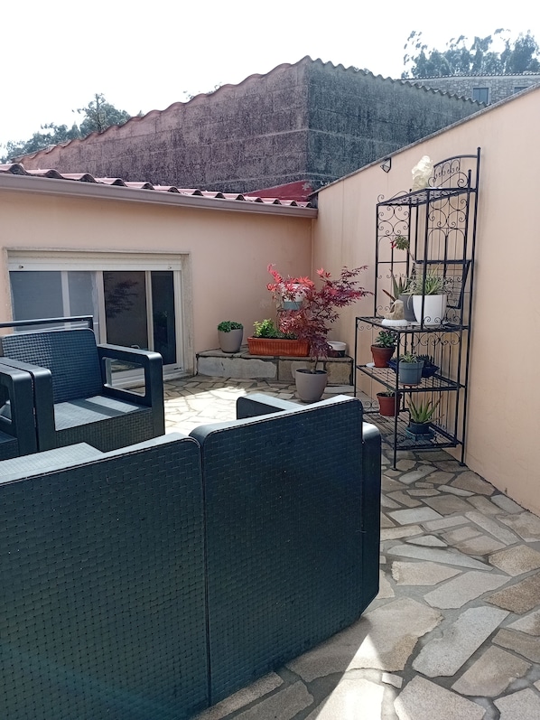 A patio area with a seating arrangement, a potted plant, and a metal plant stand. - Dorm 2 between Trega and Minho A GUARDA (A Guarda)