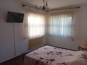 A bedroom with a bed, a radiator, a television on the wall, and two windows with sheer curtains. - Dorm 2 between Trega and Minho A GUARDA (A Guarda)