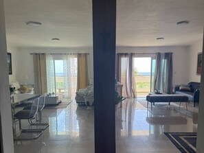Ein geräumiges Wohnzimmer mit Balkon, einer Sofagruppe, einem Couchtisch und einem Essbereich.