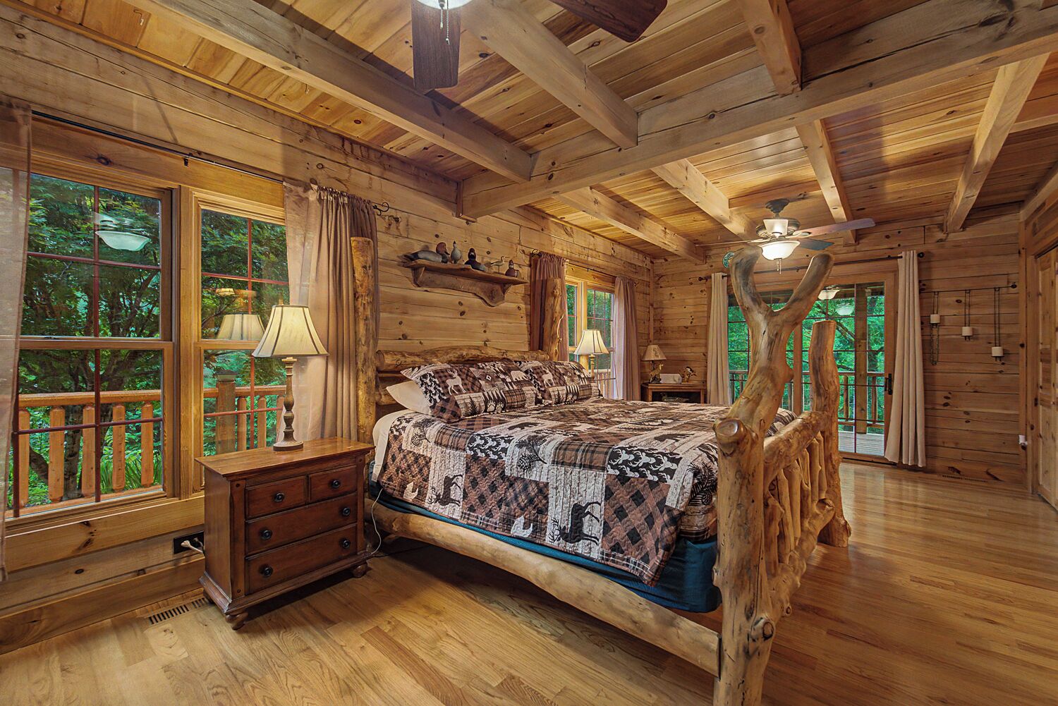 Ein Schlafzimmer in einer Blockhütte mit einem hölzernen Bett, einem Schrank und einem großen Fenster mit Vorhängen.
