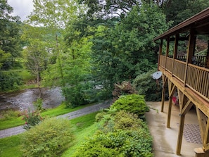 A wooden deck with a view of a river and surrounding greenery.
