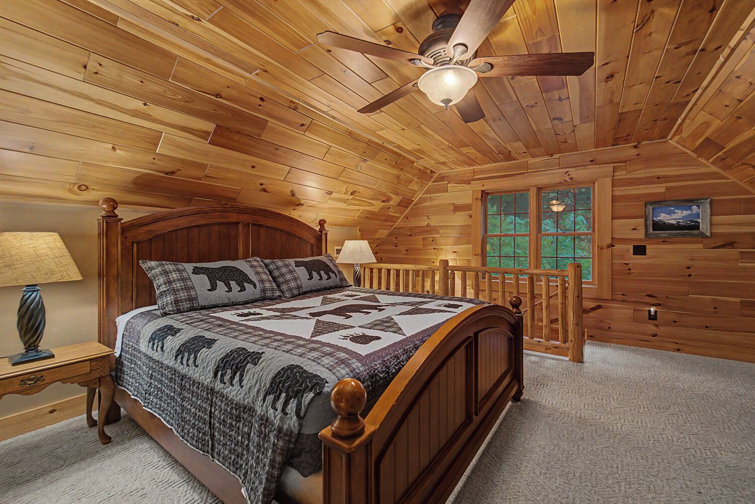 Quarto de cabana de madeira com uma cama, um ventilador de teto, uma janela e um abajur.