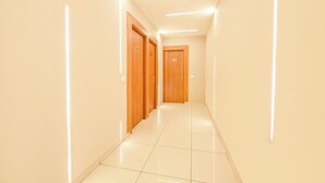 A corridor with wooden doors, white walls, and a tiled floor.