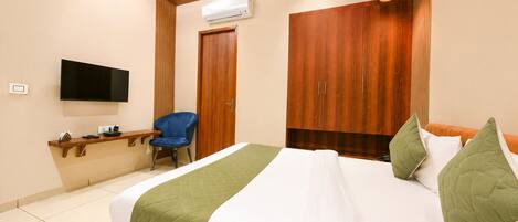 Un dormitorio con cama, televisión, silla, armario y equipo de aire acondicionado.