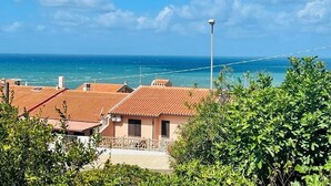 A coastal residential area with terracotta-roofed houses, a clear blue sky, and the sea in the background. - Villa with Beautiful Private Garden & Breathtaking Sea View (Porto Alabe)