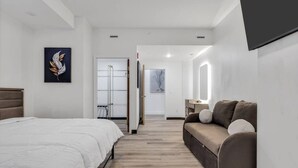 A modern hotel room with a bed, a sofa, a desk, and a large mirror. - Downtown Indy-Entire Building-77 Guests (Indianapolis)